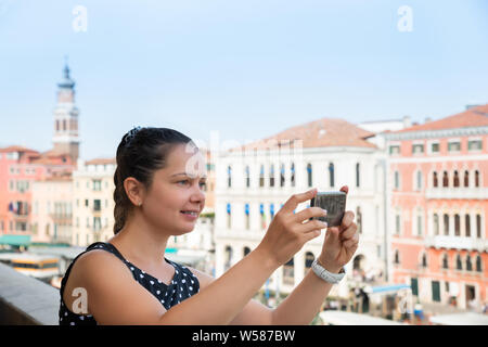 Fröhliche junge Frau Sie auf Fotos auf Handy in Venedig Stockfoto