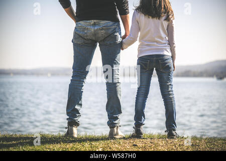 Vater und Tochter halten sich an den Händen in der Nähe vom Meer, zwei Menschen, die an der Küste in einer wunderschönen sonnigen Tag. Vati und kleine Mädchen am Horizont. Stockfoto