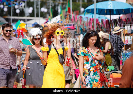 Malmesbury, Wiltshire, UK. 26. Juli 2019. Festivalbesucher genießen Sie die bunten Karneval Atmosphäre am zweiten Tag des Womad-Welt der Musik, Kunst und Tanz Festival in der schönen Außenanlage der Charlton Park Estate statt. Credit: Casper Farrell/Alamy Nachrichten Stockfoto