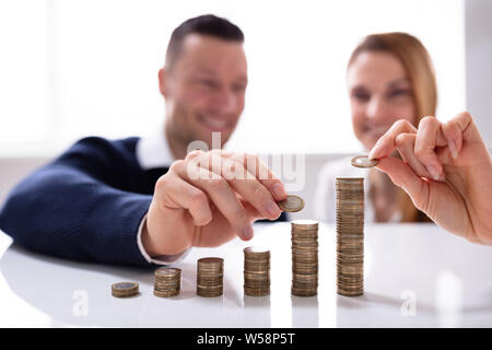 Die Paar Hand Stapeln Münzen über Weiß Schreibtisch im Büro Stockfoto