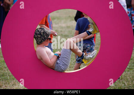 Malmesbury, Wiltshire, UK. 26. Juli 2019. Festivalbesucher genießen Sie die bunten Karneval Atmosphäre am zweiten Tag des Womad-Welt der Musik, Kunst und Tanz Festival in der schönen Außenanlage der Charlton Park Estate statt. Credit: Casper Farrell/Alamy Nachrichten Stockfoto