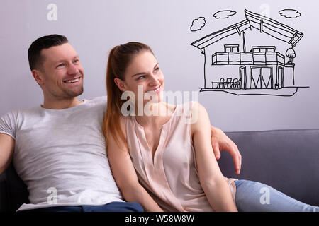 Glückliches Paar träumt von in Zukunft zu Hause auf dem Sofa sitzen Stockfoto