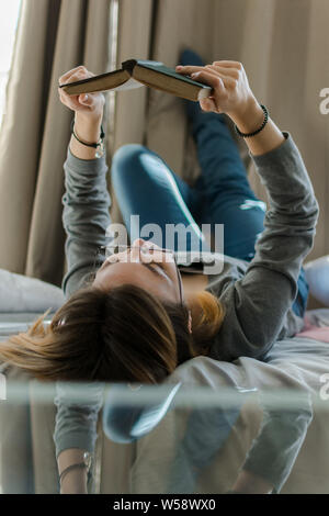 Junge Frau liest ein Buch in Ihrem Zimmer Stockfoto