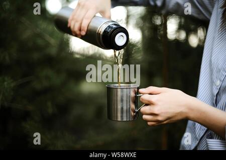 In der Nähe von Frau gießen Tee aus isolierten drink Container int Stockfoto