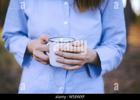 Frau traveler Hände, die Tasse Kaffee draußen. Abenteuer, Reisen, Tourismus und Camping Konzept. Wanderer Tee Trinken aus der Tasse im Camp Stockfoto