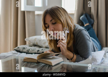 Junge Frau liest ein Buch in Ihrem Zimmer Stockfoto