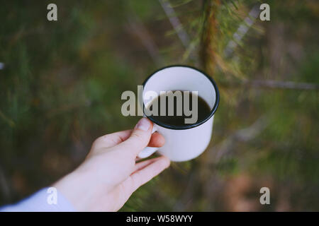 Frau traveler Hände, die Tasse Kaffee draußen. Abenteuer, Reisen, Tourismus und Camping Konzept. Wanderer Tee Trinken aus der Tasse im Camp Stockfoto