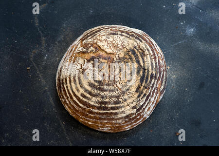 Laib Brot auf der schwarzen Oberfläche mit Mehl Stockfoto