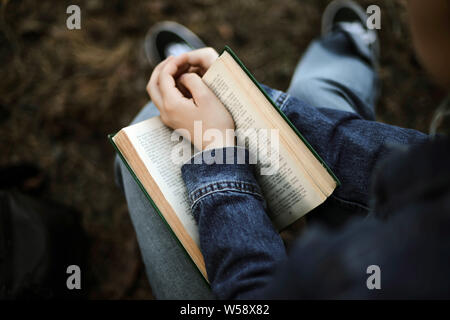 Frau mit einem Buch im Wald sitzen Stockfoto