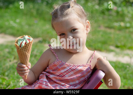 Glückliche kleine Mädchen mit Waffel Horn von Eis an Kamera im Sommer Park Stockfoto