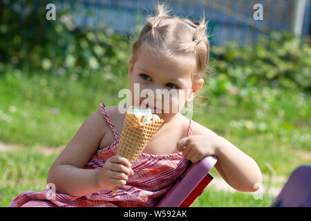 Gerne kleine Mädchen essen Waffel Horn von Eis im Sommer Park Stockfoto