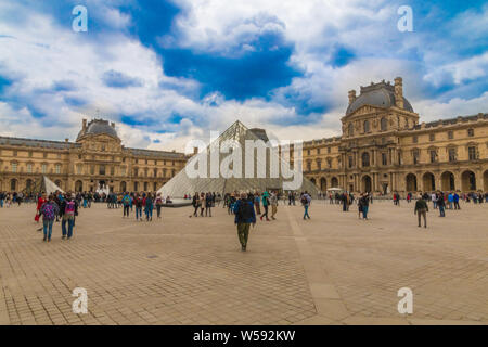 Panoramablick auf den berühmten Louvre Museum in Paris. Im Innenhof einen männlichen Besucher ist zu Fuß in Richtung der berühmten glaspyramide, einer der Louvre ist... Stockfoto