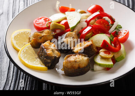 Den Europäischen Aal gebraten mit frischen Salat closeup auf einem Teller auf den Tisch. Horizontale Stockfoto