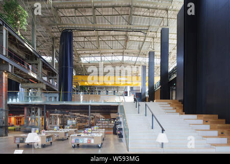 Haupttreppe und überdachte Bibliothek vom Erdgeschoss gesehen, mit Sitzbereich rechts. Bibliotheek LocHal, Tilburg, Niederlande. Architekt: CIVIC Arch Stockfoto