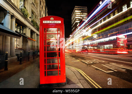 Iconic Red Telefon, klassische britische Entwurf, Stand über sich schnell bewegenden Verkehr mit leichten Wanderwegen. Stockfoto