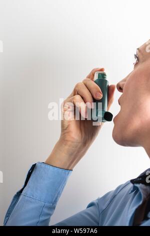 Frau mit einem Inhalator einen Asthmaanfall zu behandeln. Der Inhaler enthält bronchienerweiternde Medikamente, die verengten Atemwege in der Lunge zu erweitern. Stockfoto