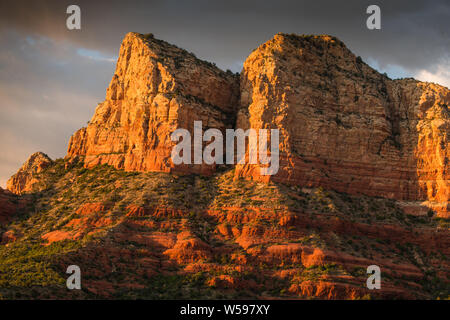 Das Licht der untergehenden Sonne leuchtet auf einem hohen Felsen unter einem dramatischen Himmel - Sedona, Arizona Stockfoto