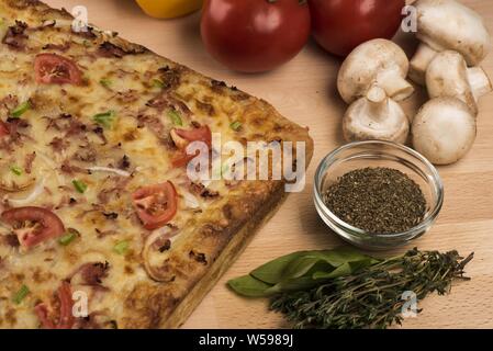 Nahaufnahme einer quadratischen Pizza mit frischen Tomaten, Paprika, Pilzen und Gewürzen Stockfoto