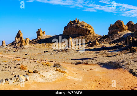 Rotbraune Piste in Richtung Wüste Felsformationen in der Morgensonne unter strahlend blauen Himmel. Stockfoto
