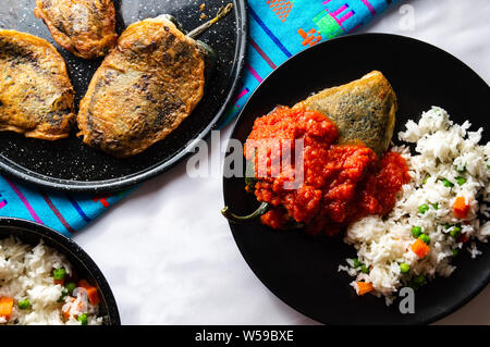 Mexikanische gefüllten Chilies (Chiles Rellenos), Poblano Chiles mit Käse gefüllt und mit einem leichten Teig beschichtet. Mit Reis und rote Tomatensauce serviert Stockfoto