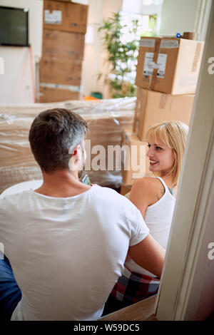 Junger Mann und Frau im neuen Zuhause. Das Sitzen auf dem Boden und entspannend nach dem Auspacken. Stockfoto