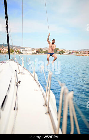 Junger Mann herumhängen, Spaß haben und genießen Sie die sommertage Sprung vom Segelboot in See. Stockfoto