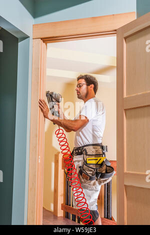 Ein Bauarbeiter tun beenden die Arbeit an einem Türrahmen innerhalb eines Hauses. Stockfoto
