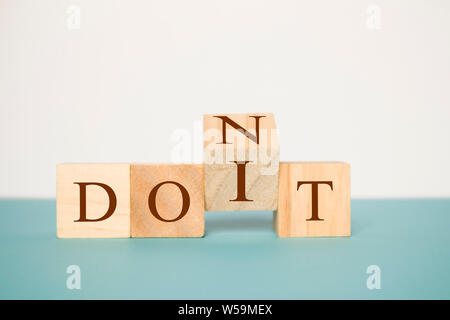 Hand spiegeln einen hölzernen Cube zu ändern das Wort nicht für tun es auf neutralem Hintergrund Stockfoto