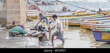 Ein Mann Wäsche waschen in traditioneller Weise in den Ganges in Varanasi. Stockfoto