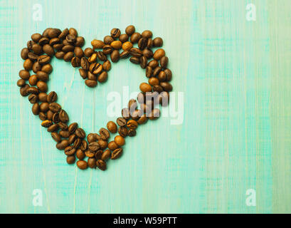 Herzform aus Kaffeebohnen auf Holz- Oberfläche Stockfoto