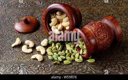 Kardamom und Cashewkerne in Holz- Utensilien auf einem schönen vintage Tabelle Stockfoto