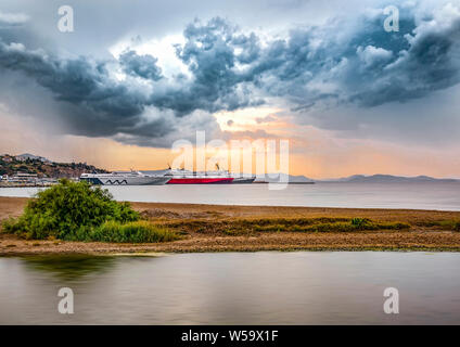 Blick auf Stadt und Hafen von Rafina unter einem dramatischen Himmel bei Sonnenuntergang Stockfoto