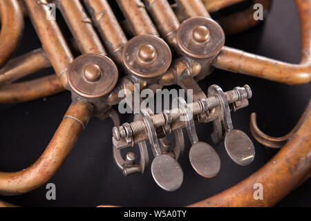Vintage Bronze Rohre, Ventil, Schlüssel mechanische Elemente Horn auf schwarzem Hintergrund. Gutes Muster, prompt Musik Instrument. Stockfoto
