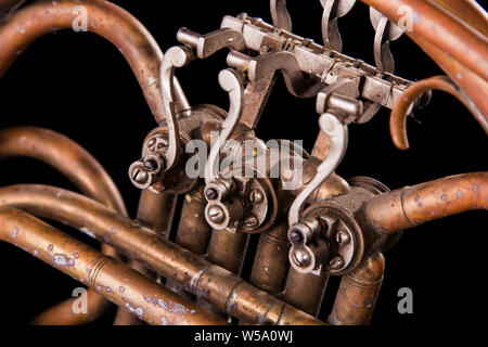 Vintage Bronze Rohre, Ventil, Schlüssel mechanische Elemente Horn auf schwarzem Hintergrund isoliert. Gutes Muster, prompt Musik Instrument. Stockfoto