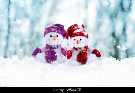 Zwei kleine Schneemänner das Mädchen und der Junge in Mützen und Schals auf Schnee im Winter. Festliche Hintergrund mit einem lustigen Schneemann. Weihnachtskarte, kopieren. Stockfoto