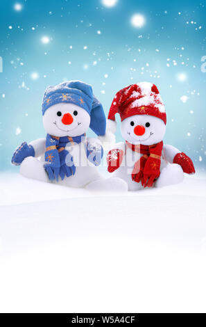 Zwei kleine Schneemänner das Mädchen und der Junge in Mützen und Schals auf Schnee im Winter. Festliche Hintergrund mit einem lustigen Schneemann. Weihnachtskarte, kopieren. Stockfoto