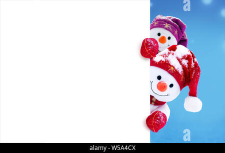 Zwei kleine Schneemänner das Mädchen und der Junge in Mützen und Schals auf Schnee im Winter. Festliche Hintergrund mit einem lustigen Schneemann. Weihnachtskarte, kopieren. Stockfoto