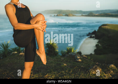 Junge athletische Sportlerin Stretching und Vorbereitung für den Außenbereich yoga Workout. Sport und aktiv leben Konzept. Natur Hintergrund. Stockfoto