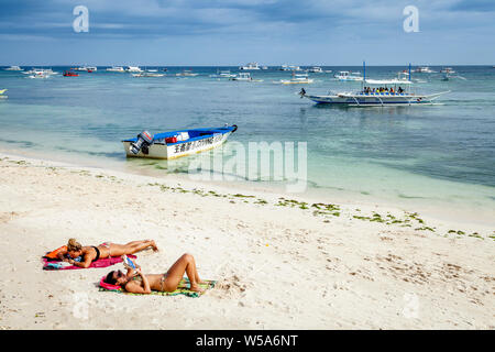 Junge Frauen beim Sonnenbaden auf Alona Beach, Bohol, Philippinen Stockfoto