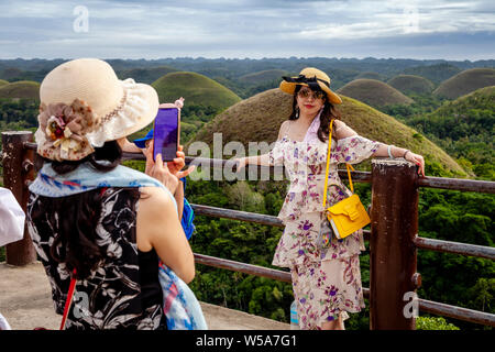 Chinesische Besucher für Fotos zu den Chocolate Hills Aussichtsplattform, Carmen, Bohol, Philippinen Posing Stockfoto