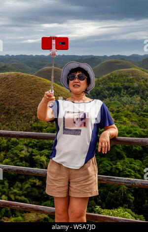 Eine asiatische Frau, eine selfie an der Chocolate Hills Aussichtsplattform, Carmen, Bohol, Philippinen Stockfoto