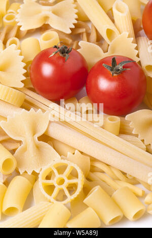 Hintergrund mit verschiedenen Arten und Formen von Nudeln und zwei rote Tomaten Stockfoto