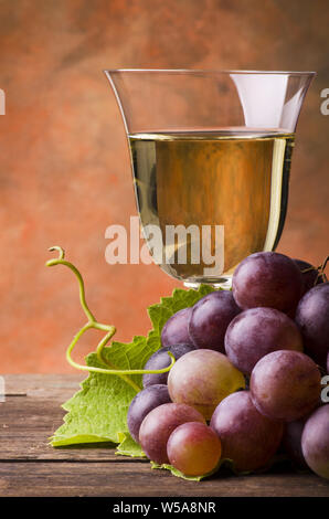 Auf rustikalen Holztisch Strauß roter Trauben auf dem Glas Wein Hintergrund Stockfoto