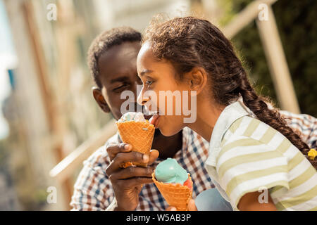 Gerne dunkelhäutiger Jugendlicher essen Eis-Creme von ihrem Vati Stockfoto