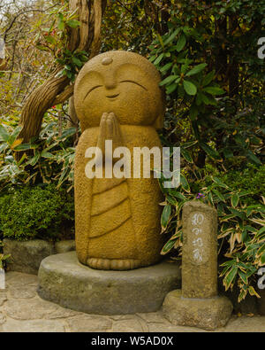 Kleine steinerne Statue eines kleinen betenden Mönch in einem komisch aussehende Gestalt mit reichen Details, Hase-dera Kamakura Japan 2018 Stockfoto