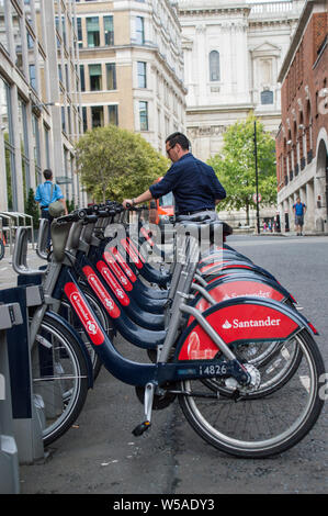 Ein erwachsener Mann, der ein santander Fahrrad / Fahrrad ausdockt Die Andockstation von ride sharing Santander Cycles dockt an Die Londoner Stadt Stockfoto