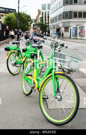 E-Bikes / E-Bikes von Lime-E auf Bürgersteig in London geparkt Stockfoto