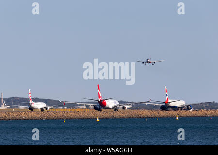 Jetstar Airbus A320 am Ansatz am Sydney Flughafen mit einer Jungfrau, Qantas Boeing 737 Airbus A330 und British Airways Boeing 777 auf der Straße zu landen. Stockfoto