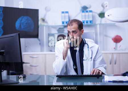 Männlicher Arzt in einer Videokonferenz und ein Gespräch mit einem Patienten. Arzt auf seine Arbeit konzentriert. Stockfoto