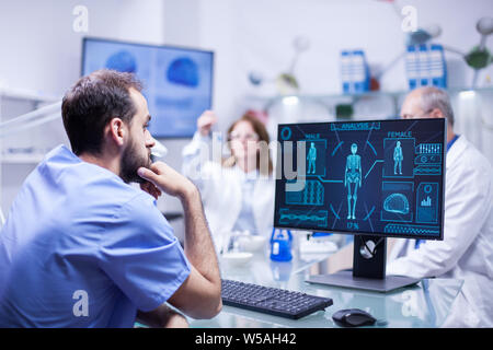Junge Techniker, Überwachung und Bewertung der männlichen System in der Wissenschaft. Weibliche Specialist bei der Arbeit mit Röhren im Hintergrund. Stockfoto